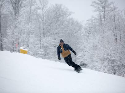 Snowboarder heading down hill at Kissing Bridge